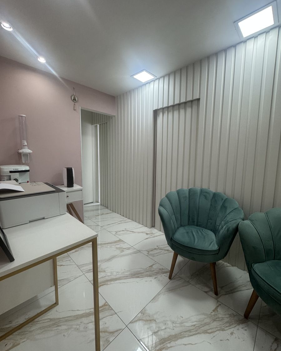Área de espera com poltronas verdes e piso de mármore