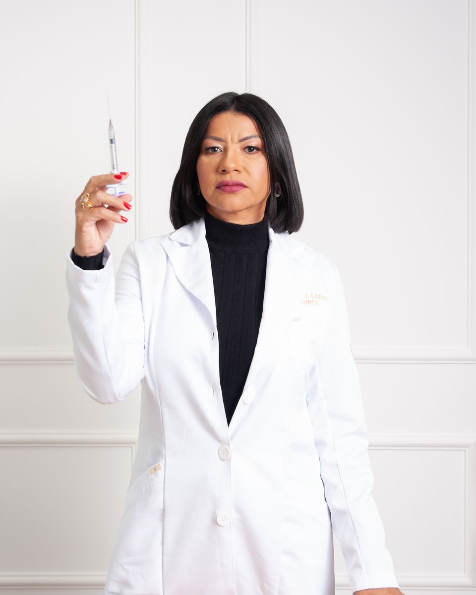 Dra. Neuma Lopes de jaleco segurando uma seringa